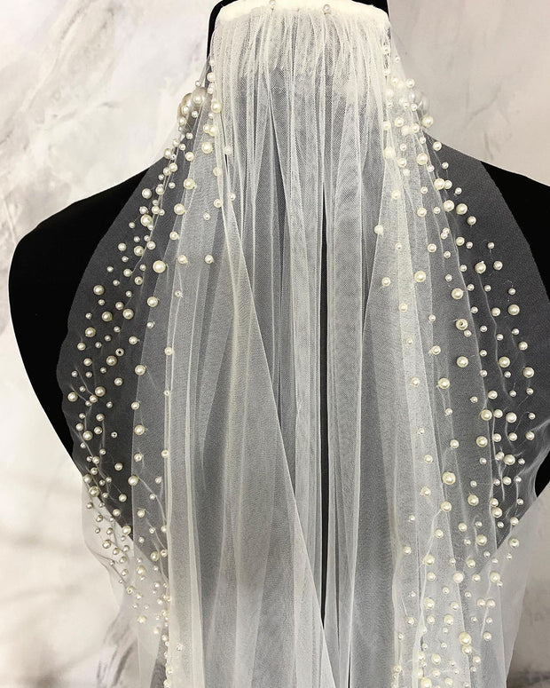 Wedding veil with pearls. A scattering of pearls along the edge of the veil.